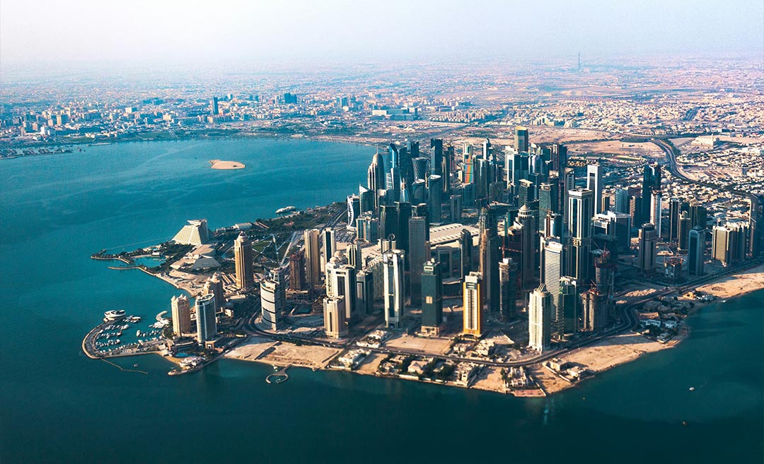 Aerial panoramic view of the modern Doha cityscape and skyline at Hamad International Airport hub in Qatar.