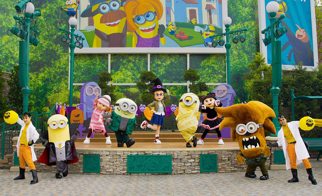 A live street performance at Universal Studios Singapore featuring costumed Minion characters, including Mummy Stuart and Vampire Kevin, during a festive event from the Despicable Me franchise.